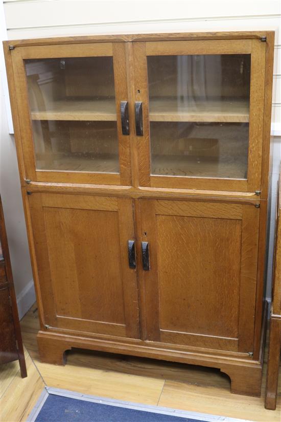 A Gordon Russell oak cupboard, fitted with a pair of glazed doors over panelled doors W95.5cm H170cm